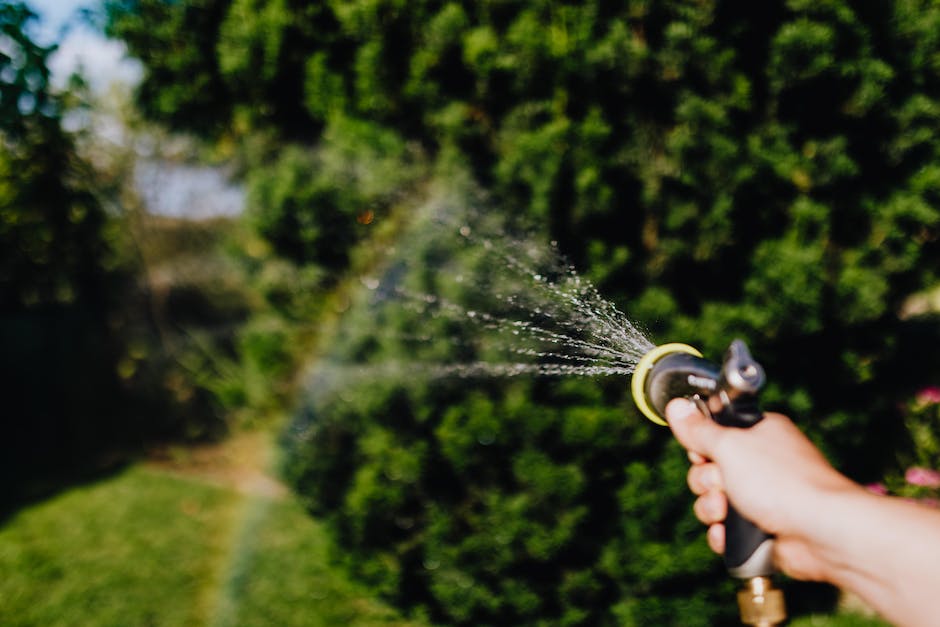 A person using a garden hose to drain water from an Intex Simple Spa Hot Tub